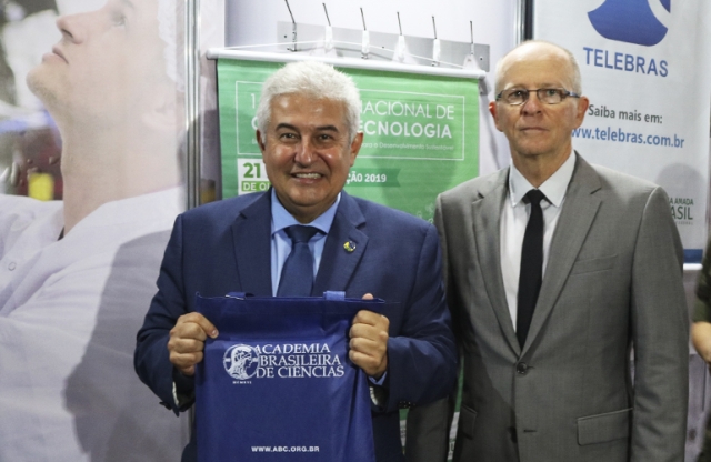 Ministro Marcos Pontes recebendo a publicação do centenário da Academia Brasileira de Ciências pelas mãos do acadêmico Elíbio Rech